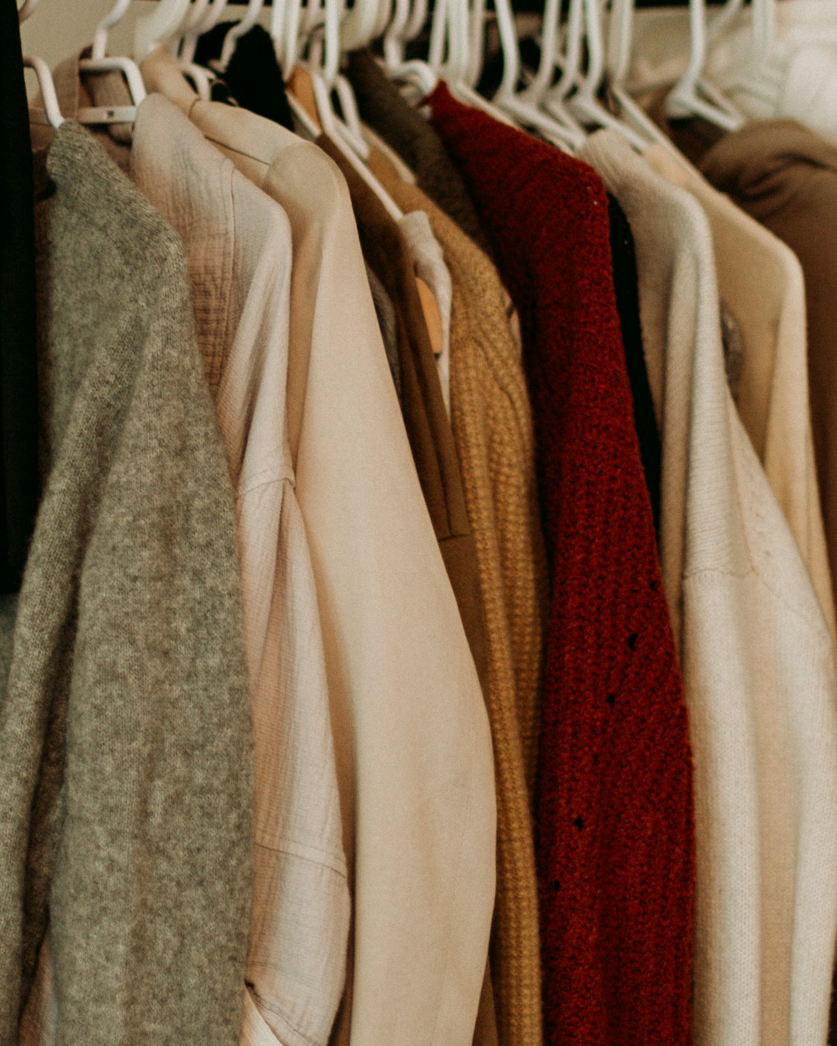 Neutral knitwear and shirts arranged on a clothing rail