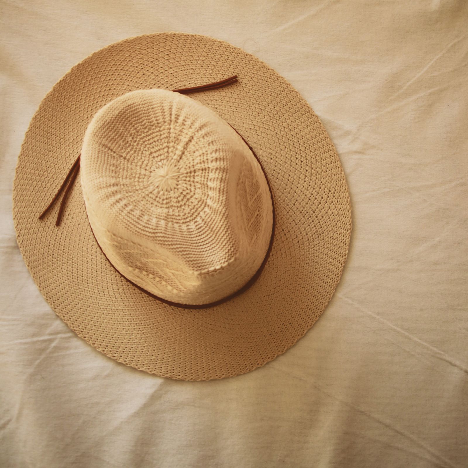 Woven straw hat resting on neutral linen fabric